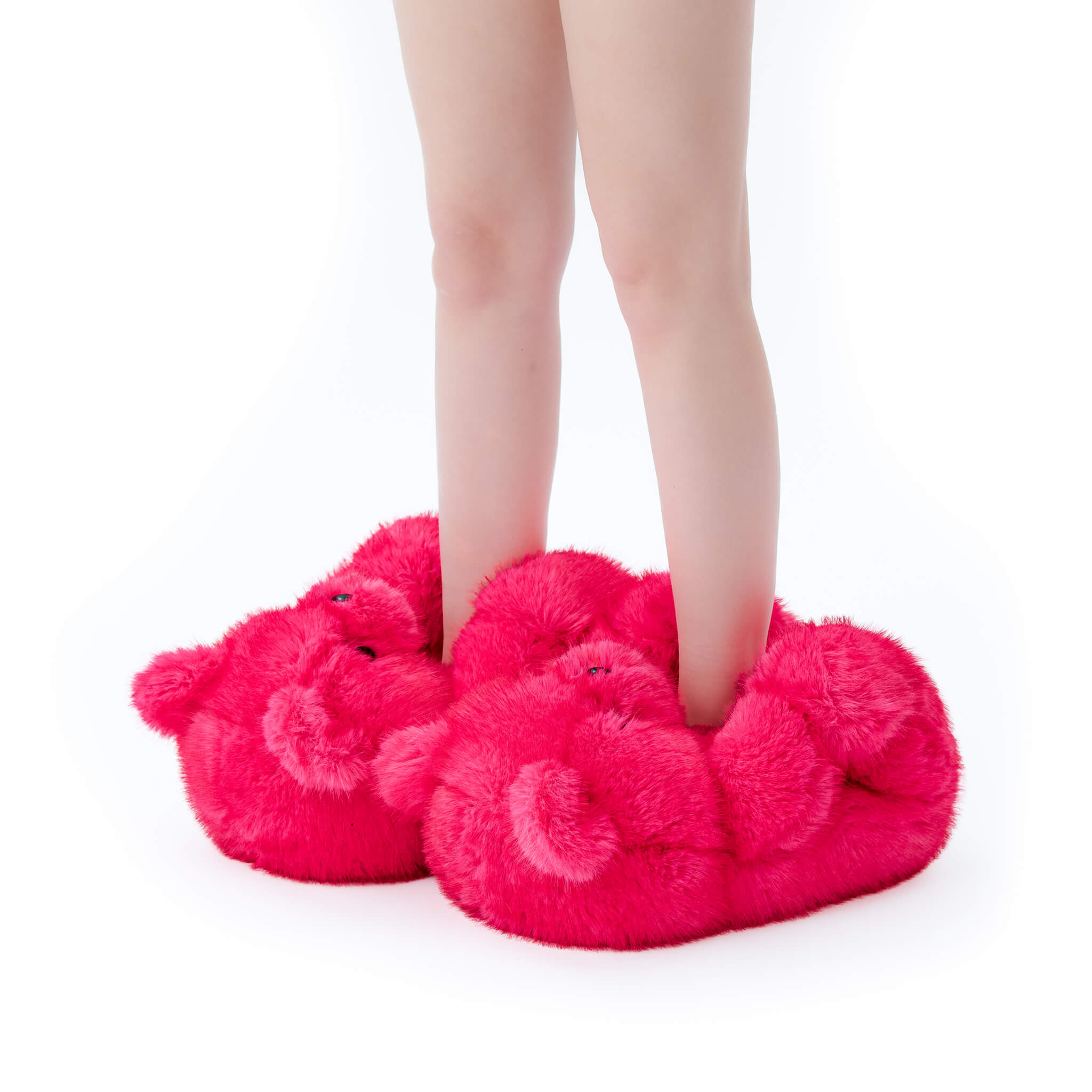 Person wearing bright pink fuzzy slippers shoes on a white background